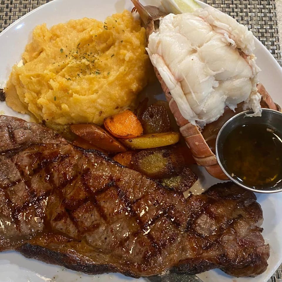 Randy's Bistro surf and turf with grilled steak, lobster tail, mashed potatoes, and roasted vegetables.