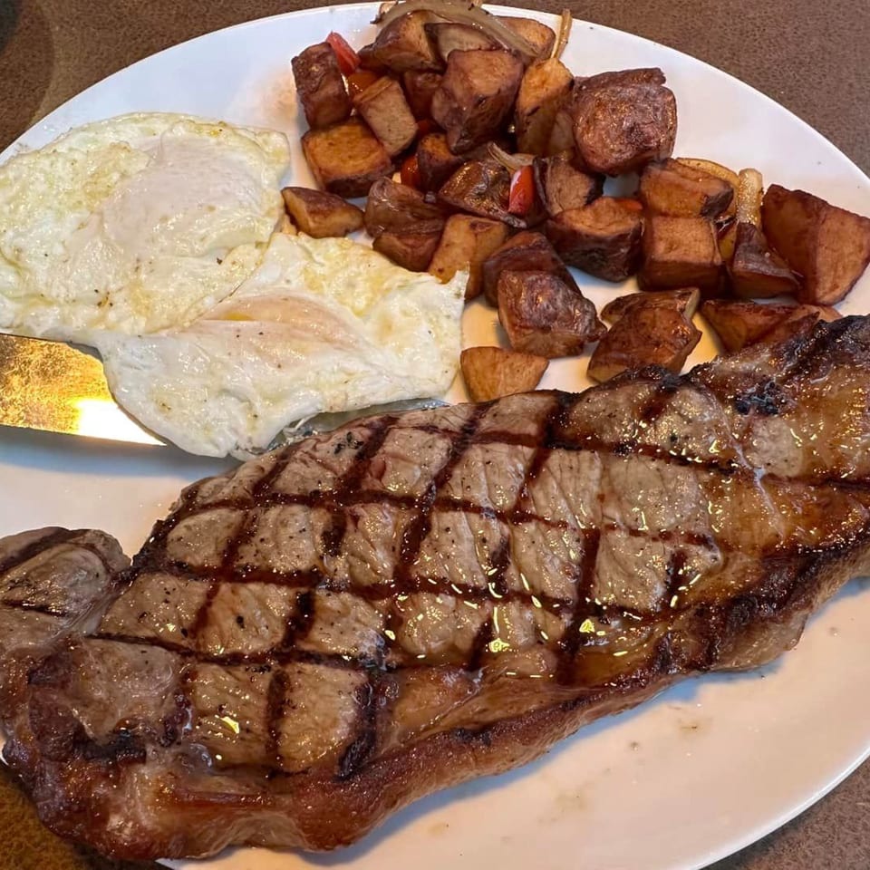 Randy's Bistro's steak and eggs with home fries on a white plate.